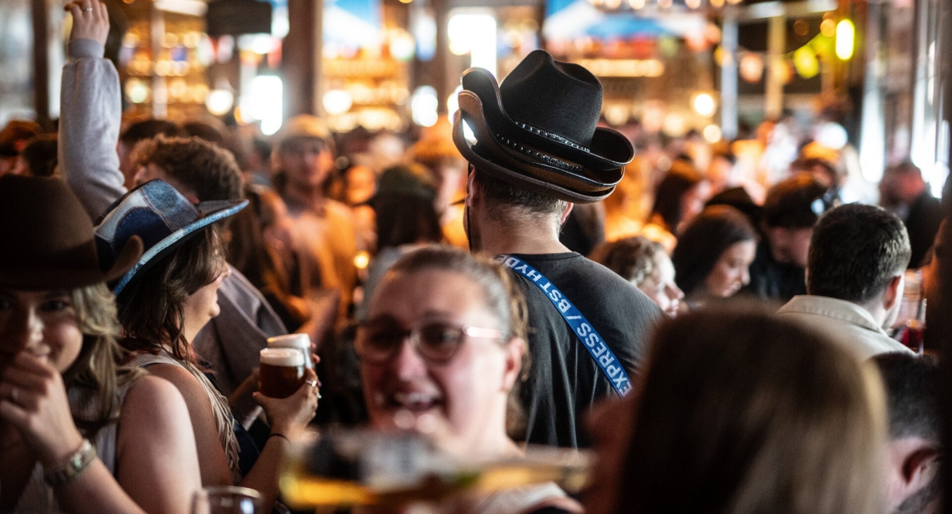 Bar full of people, with several people wearing cowboy hats.