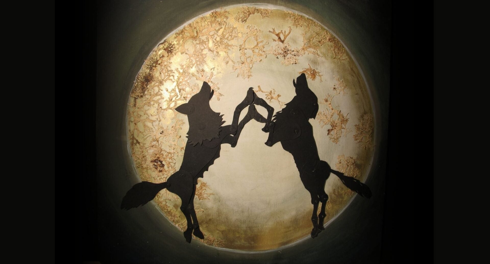 Picture of a moon, with 2 howling wolves.