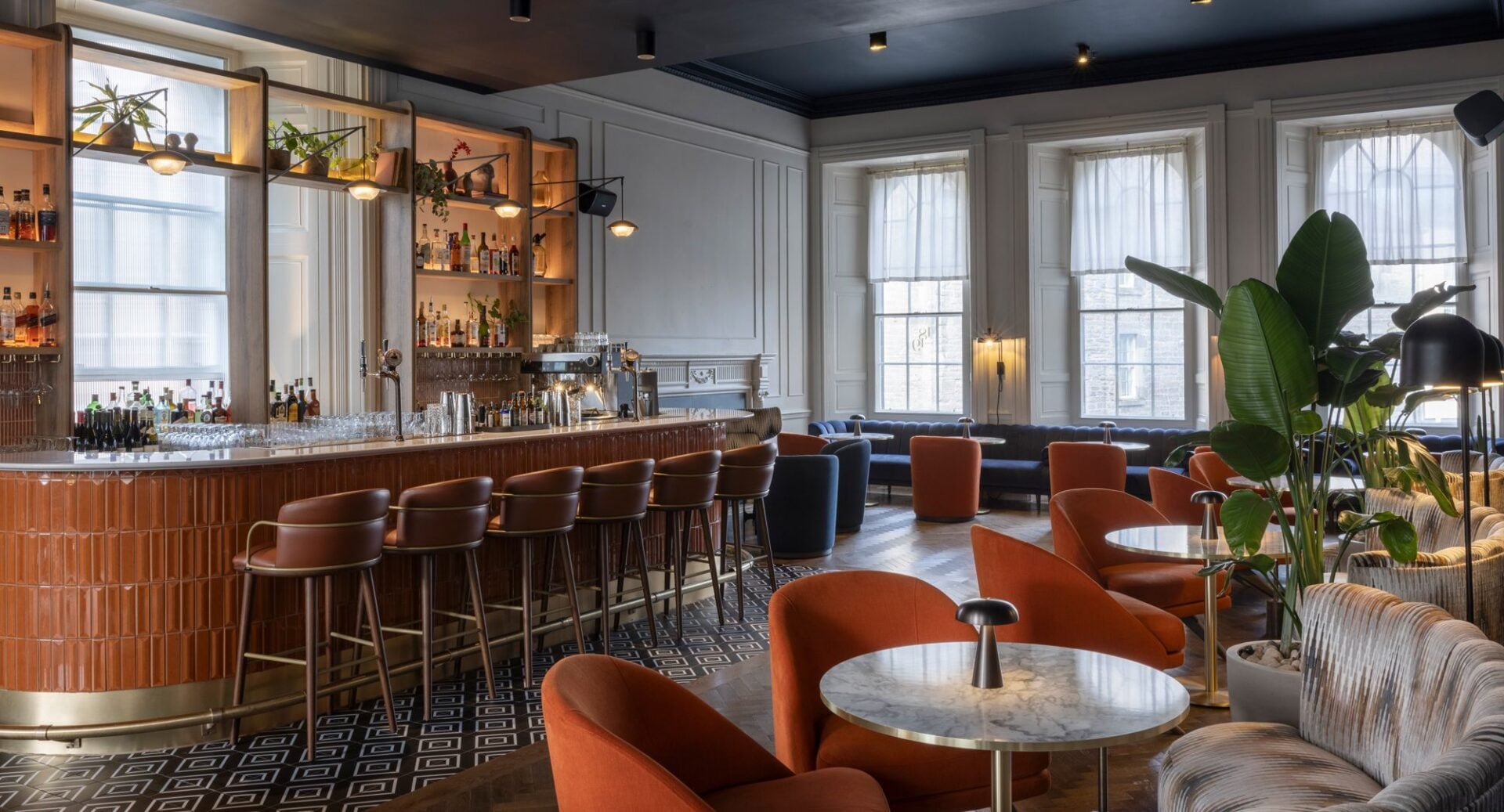 A bar area, complete with a row of stools at the bar, and individual tables and chairs around the room.