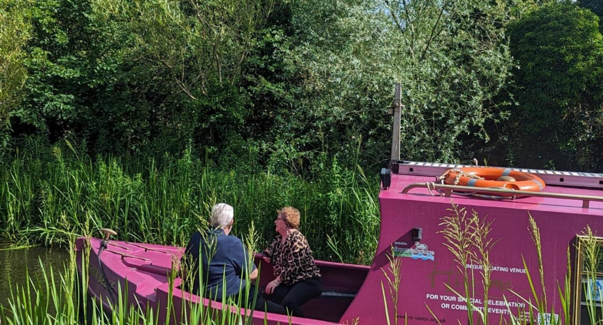 A couple sitting in a purple canal boat.