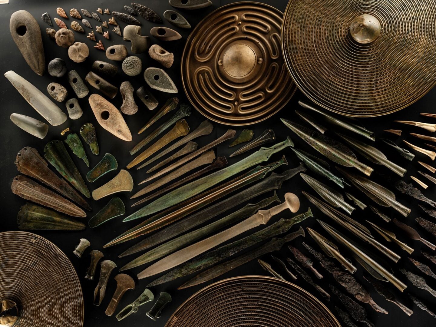A collection of metal and stone objects, including shields and daggers.