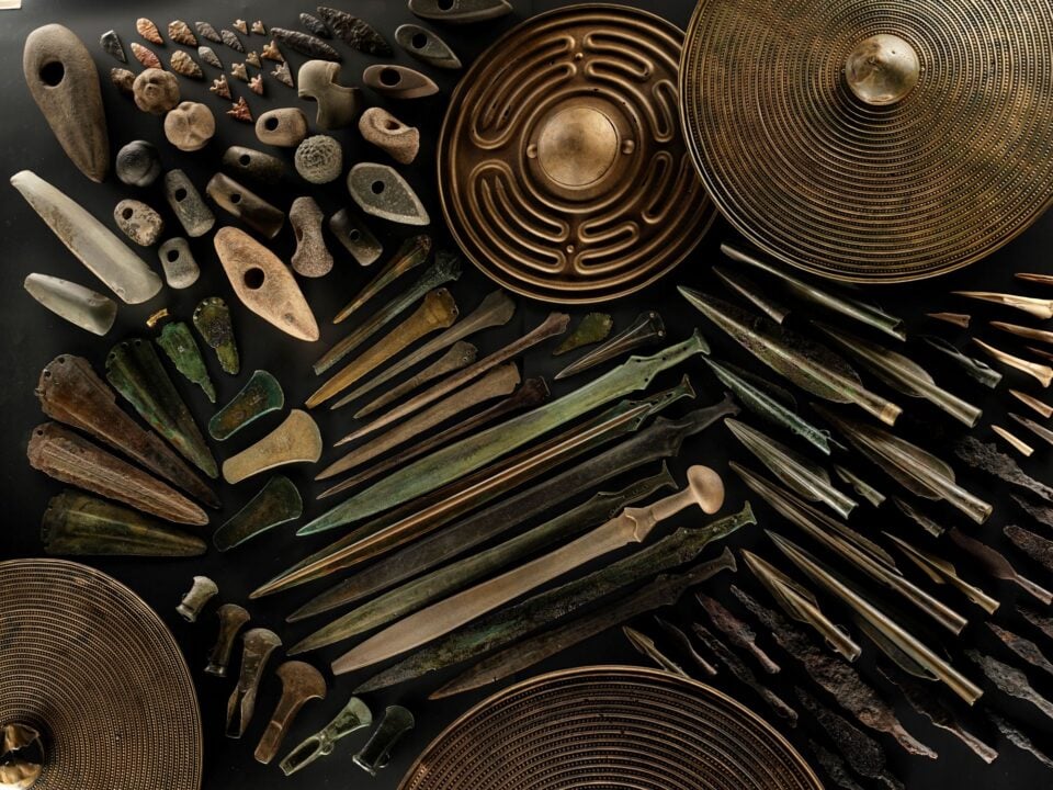 A collection of metal and stone objects, including shields and daggers.
