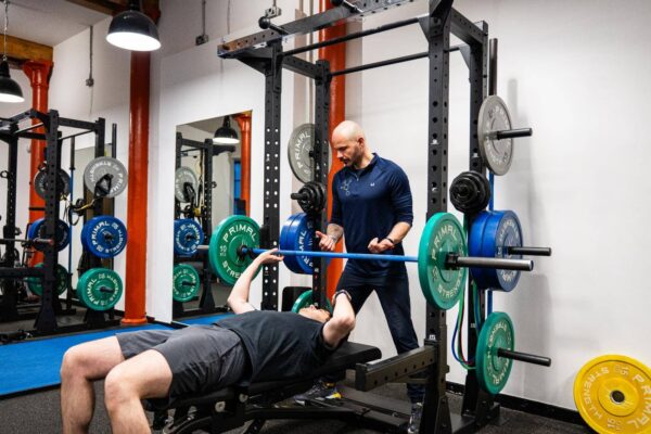 Person in gym being helped by Personal Trainer from Health by Science Personal Training