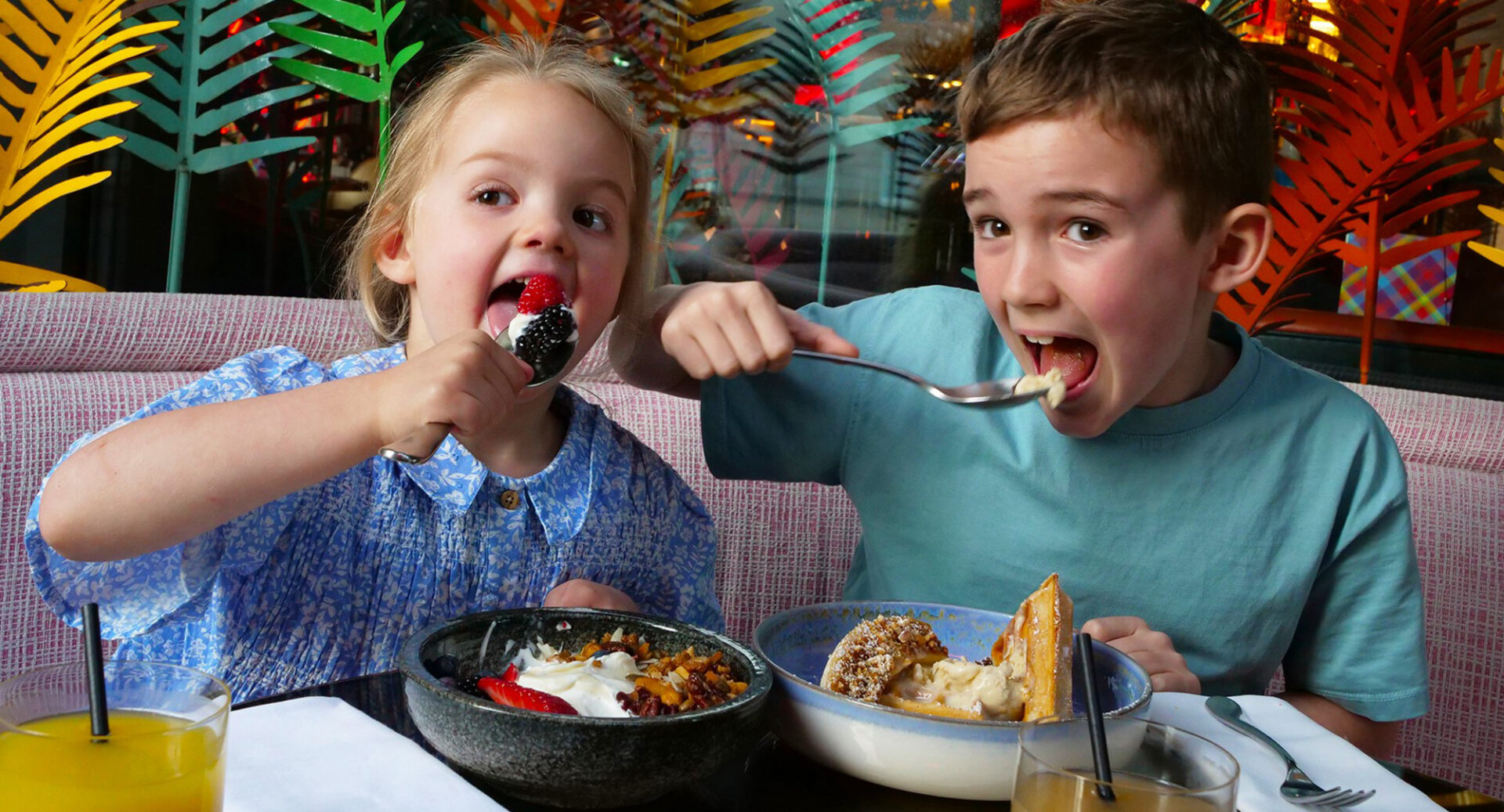 2 young children eating food in a restaurant.
