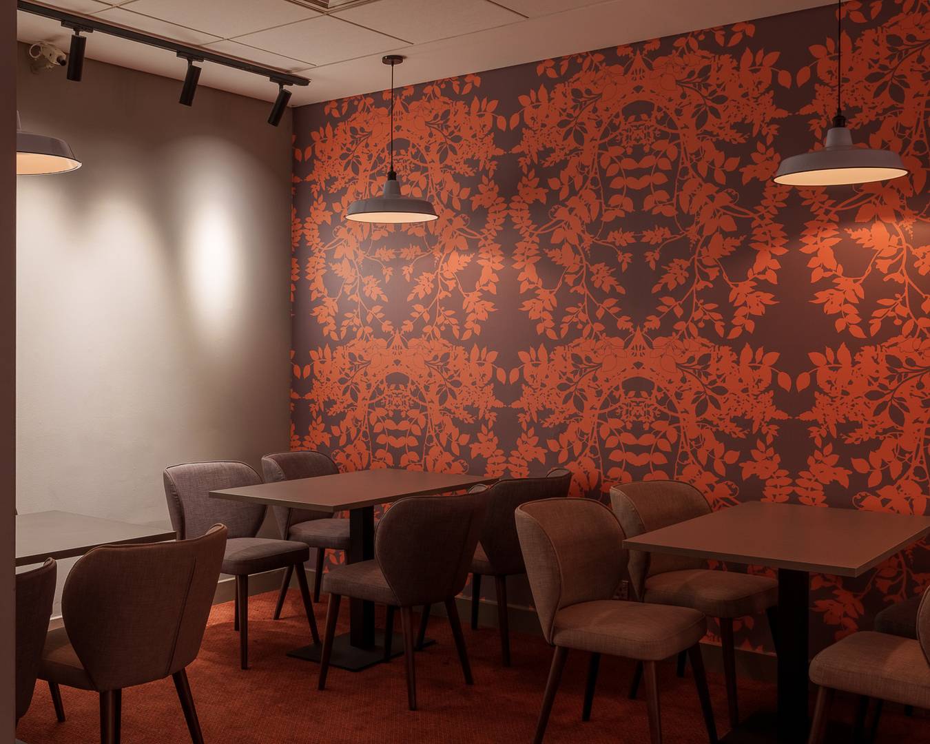 Filmhouse bar café, there are tables with chairs against a wall, which has red and grey patterned wallpaper. There are metal lampshades over each table and low lighting.,© Alexander Thomas