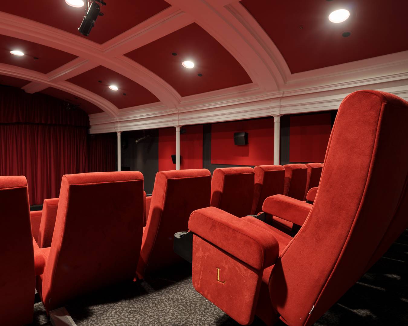 Filmhouse cinema 1. There are rows of red cinema chairs, facing a stage which has a red curtain hanging. The ceiling is arches and painted red and white.,© Alexander Thomas