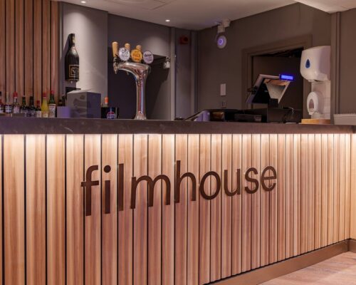 A bar panelled with light ash wood. There is the Filnhouse logo in metal on top of the panels. There is also drinks and beer taps on display.,© Alexander Thomas