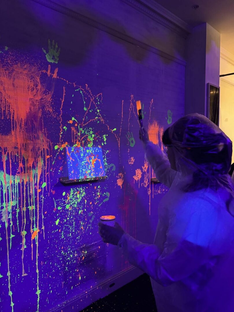 Someone splashing their neon paint onto their canvas.