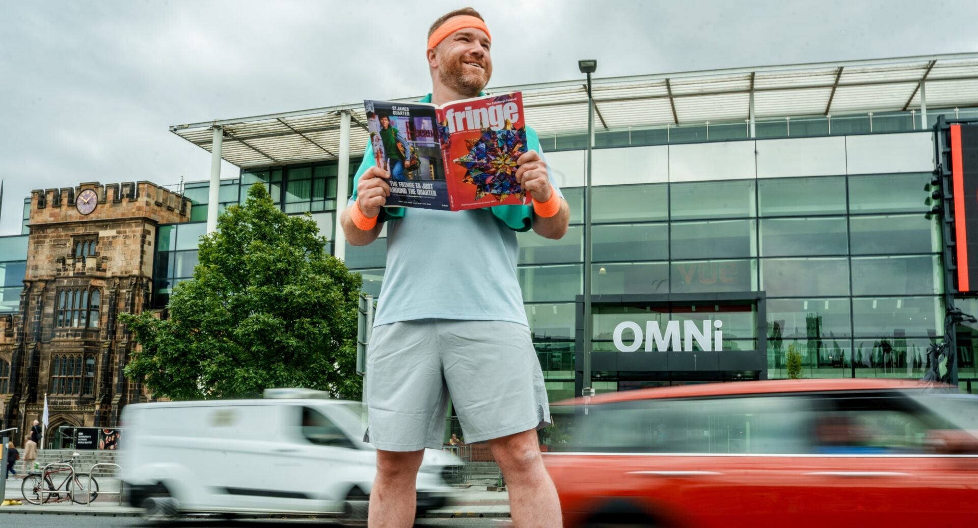 A man holding a brochure, while standing at the side of a road.