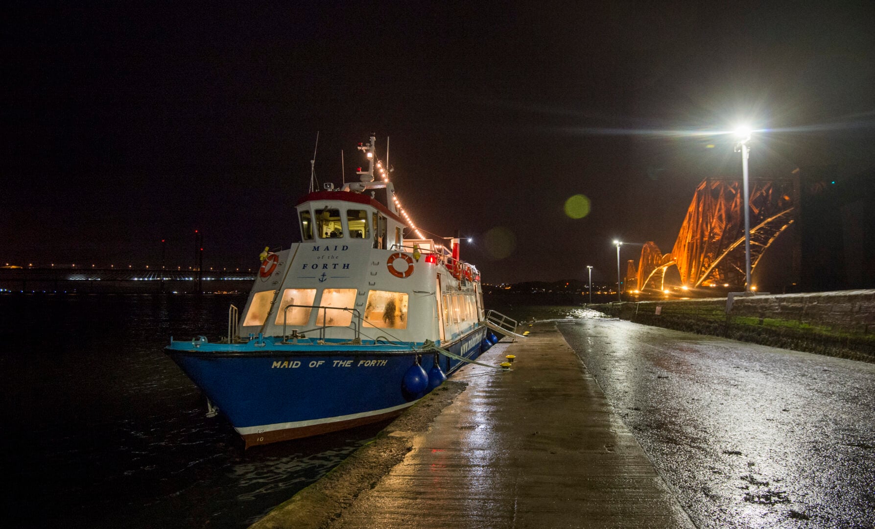 Maid of the Forth boat at night next to Forth Bridge