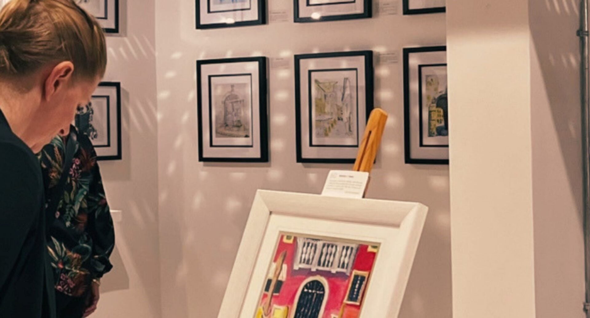 Close-up of a woman looking at a painting on an easel.