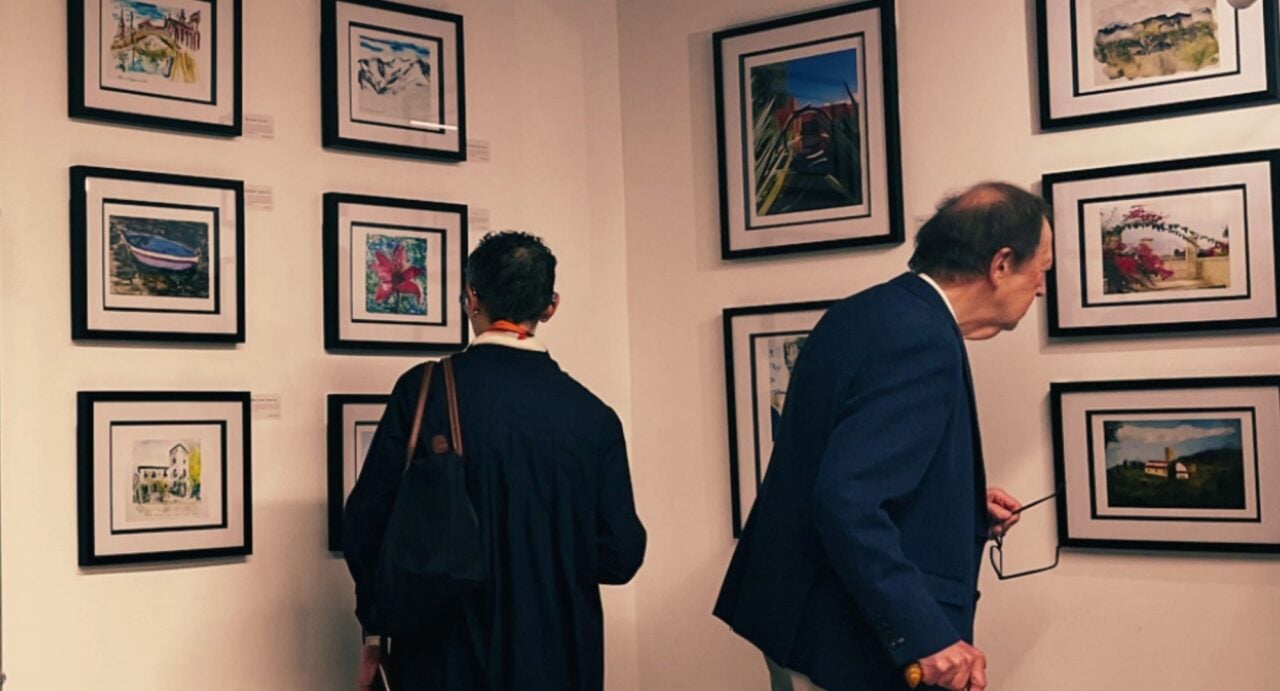 2 people looking at a series of landscape images on a wall.