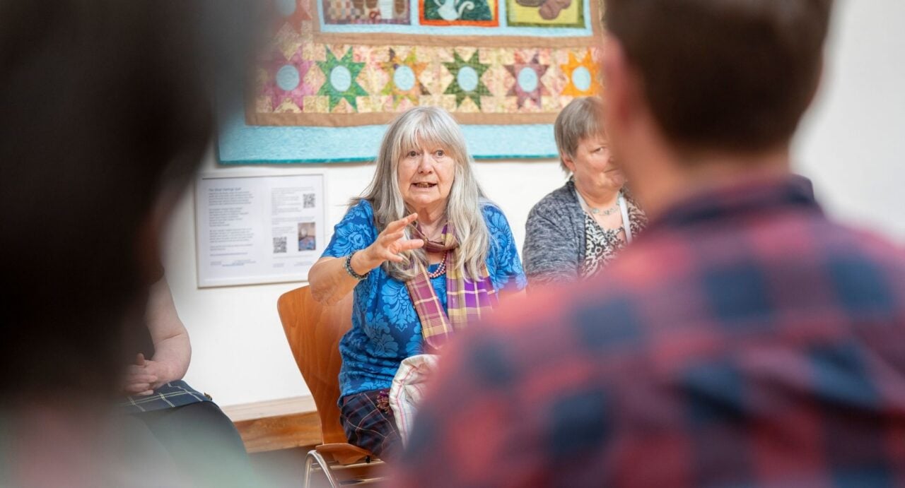 2 seated woman talking to an audience.
