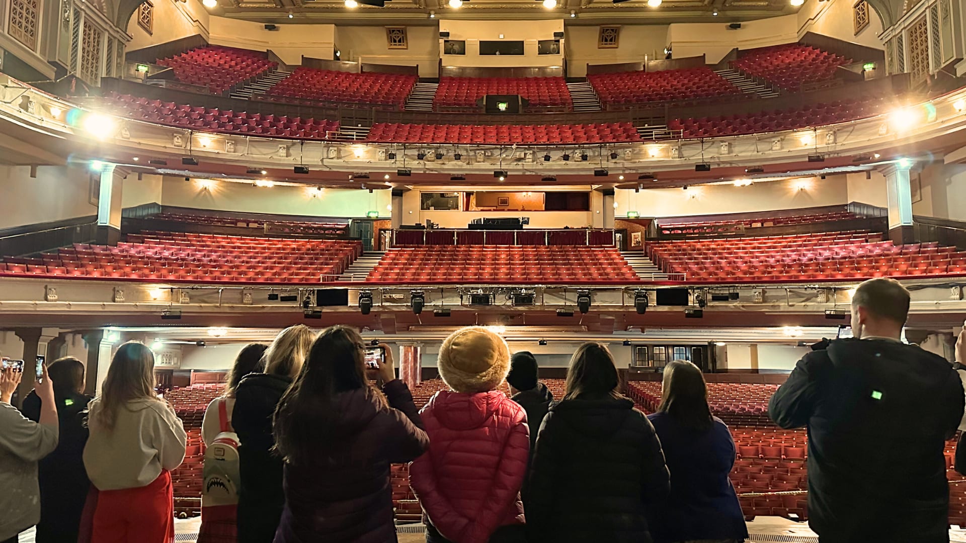 A group of people standing on a theatre stage, looking out at the auditorium.