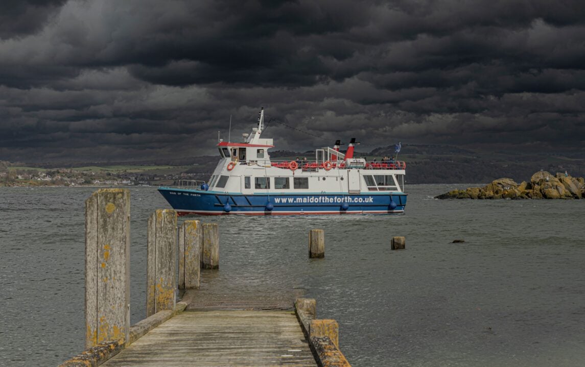 A boat ont eh water and a dark, cloudy sky