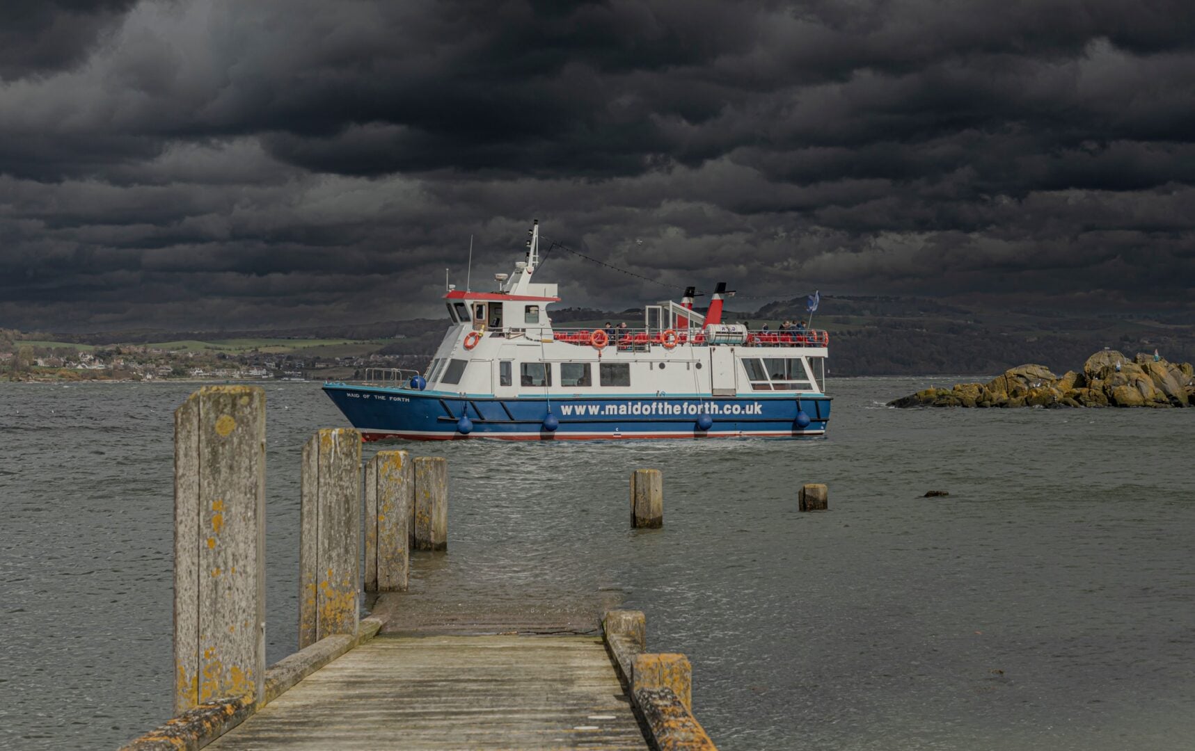 A boat ont eh water and a dark, cloudy sky