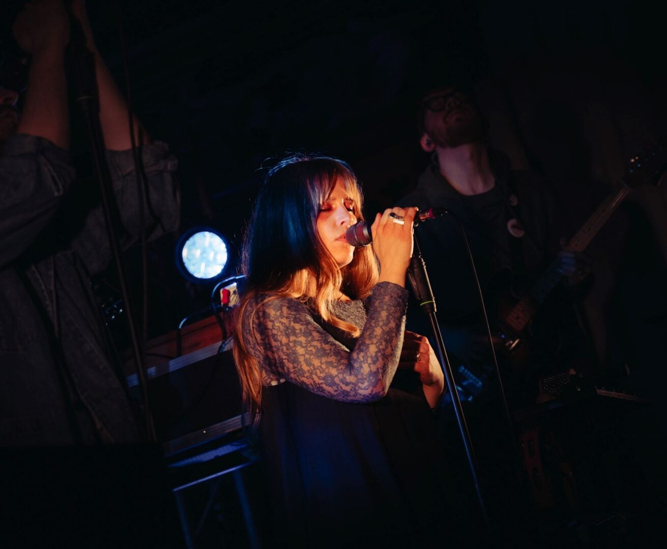 A woman on stage, singing into a microphone.