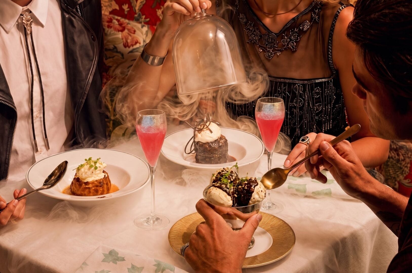 4 people seated at a dining table, with plates of food in front of them.