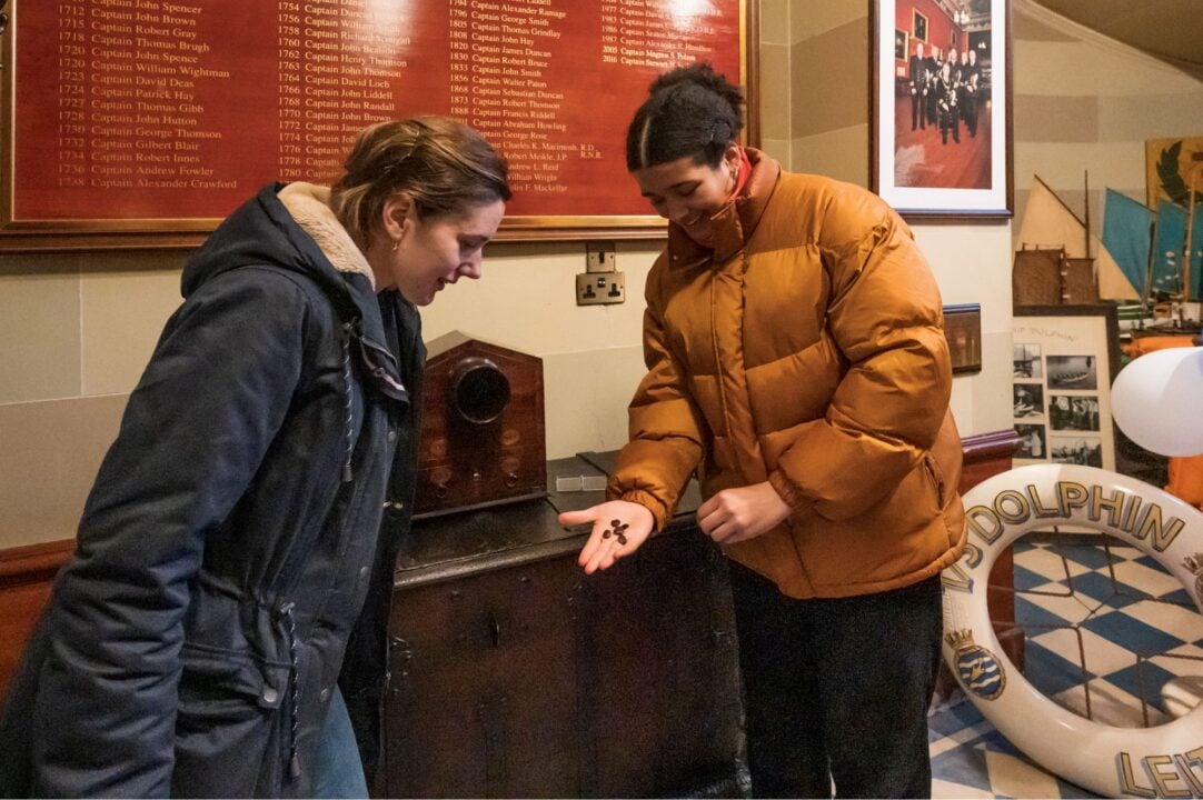2 people looking at bean-like objects in one of the person's outstretched hand.