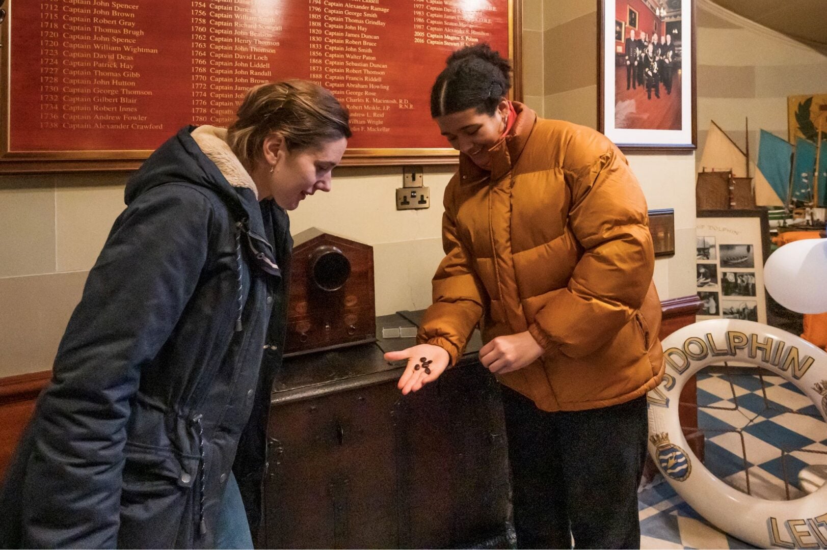 2 people looking at bean-like objects in one of the person's outstretched hand.