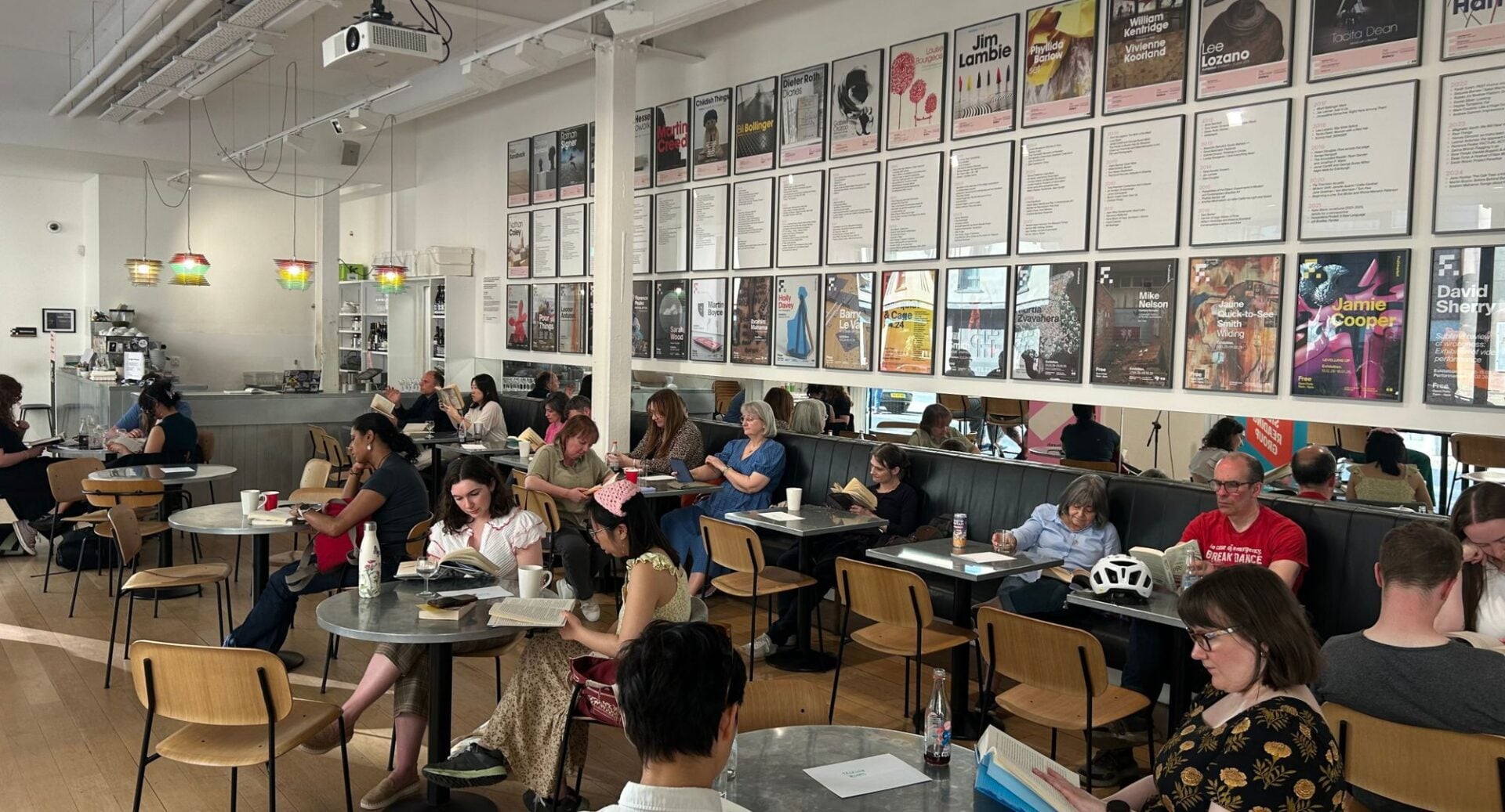 People seated in a cafe, each reading a book.