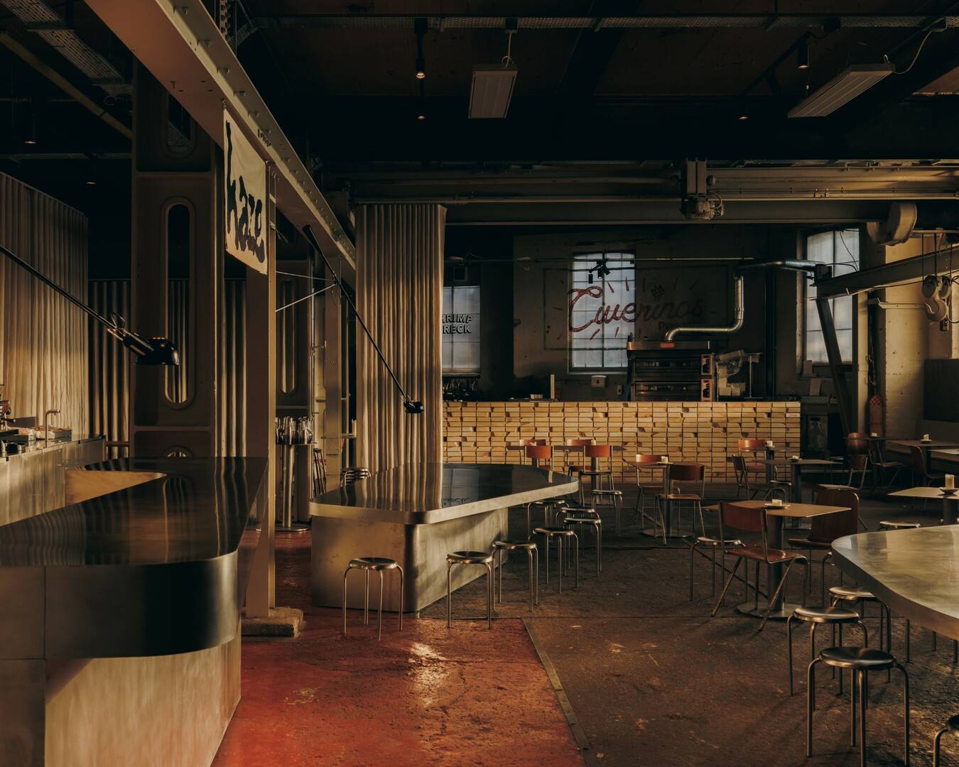 Main hall at Brown's of Leith, a former engineering works. A stainless steel bar runs along the left under linen curtains and a steel gantry crane.,© Richard Gaston for GRAS