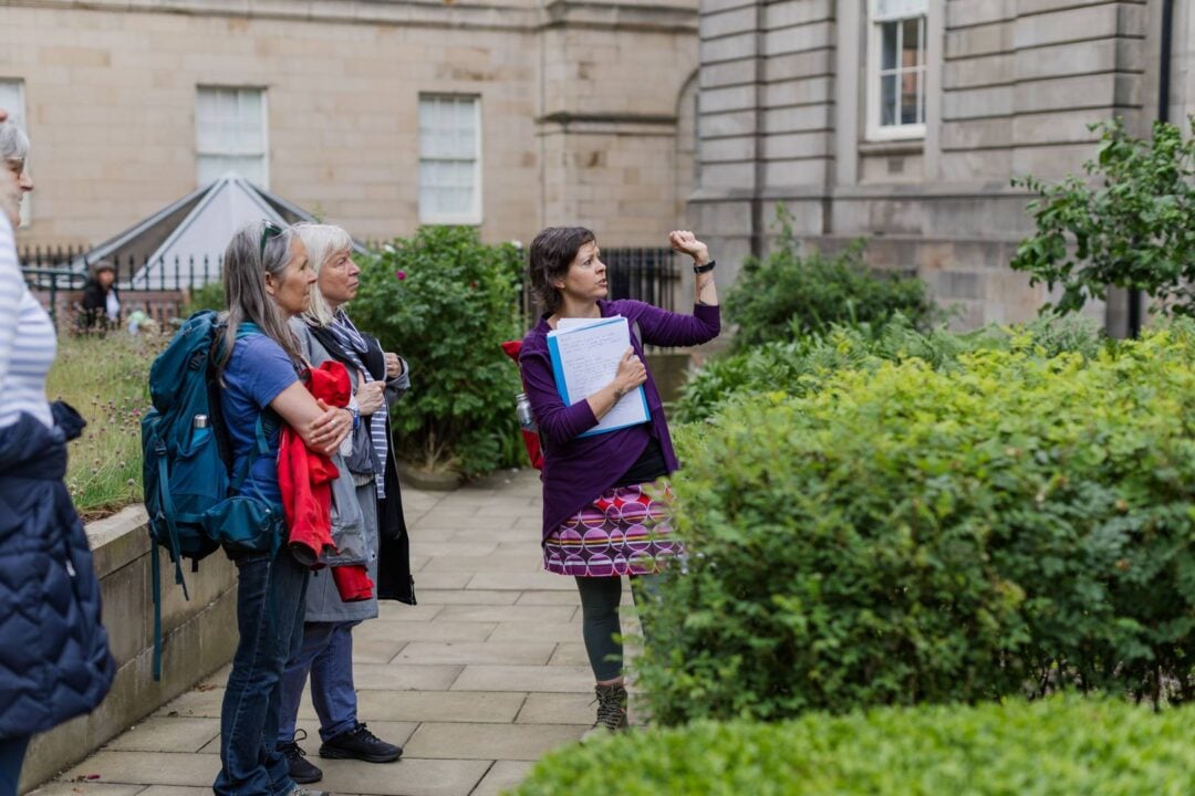 Guide standing in the Archivists' Garden in front of a Rowan tree in Edinburgh,© Women in Travel CIC
