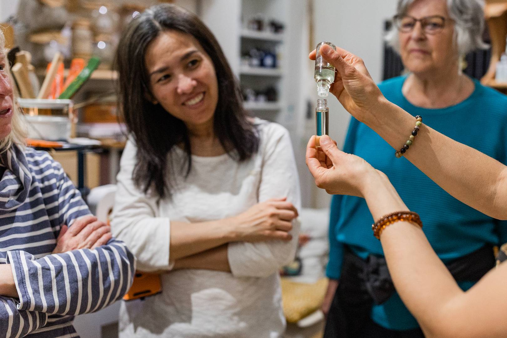 Aromatherapy workshop, three women watching aromatherapist mix essential oils in a small bottle ,© Women in Travel CIC