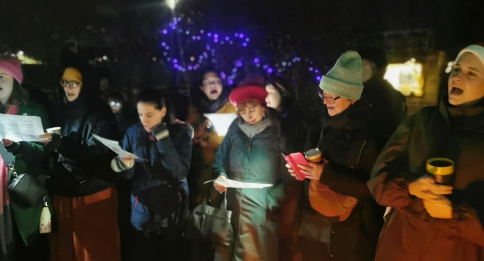 A group of people singing outdoors.
