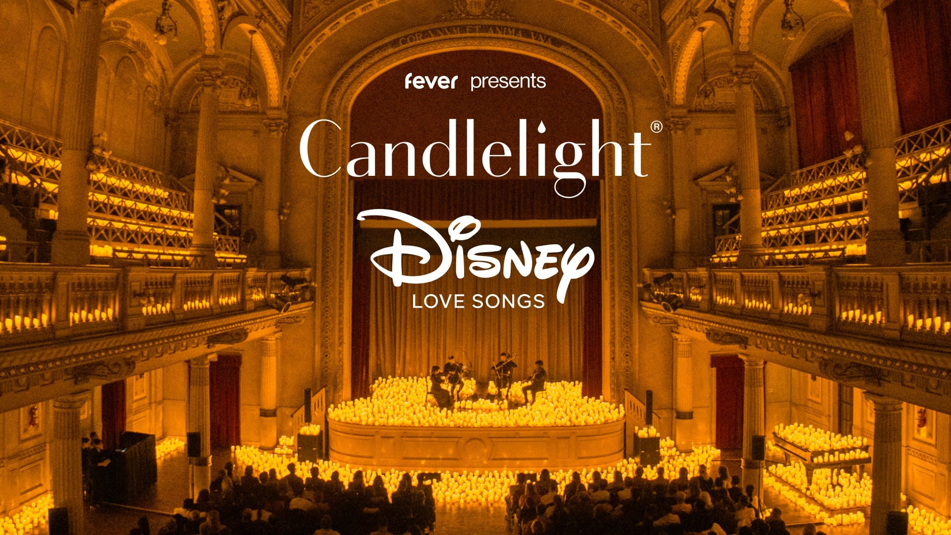 An orchestra performing on stage within a church setting, surrounded by candles.