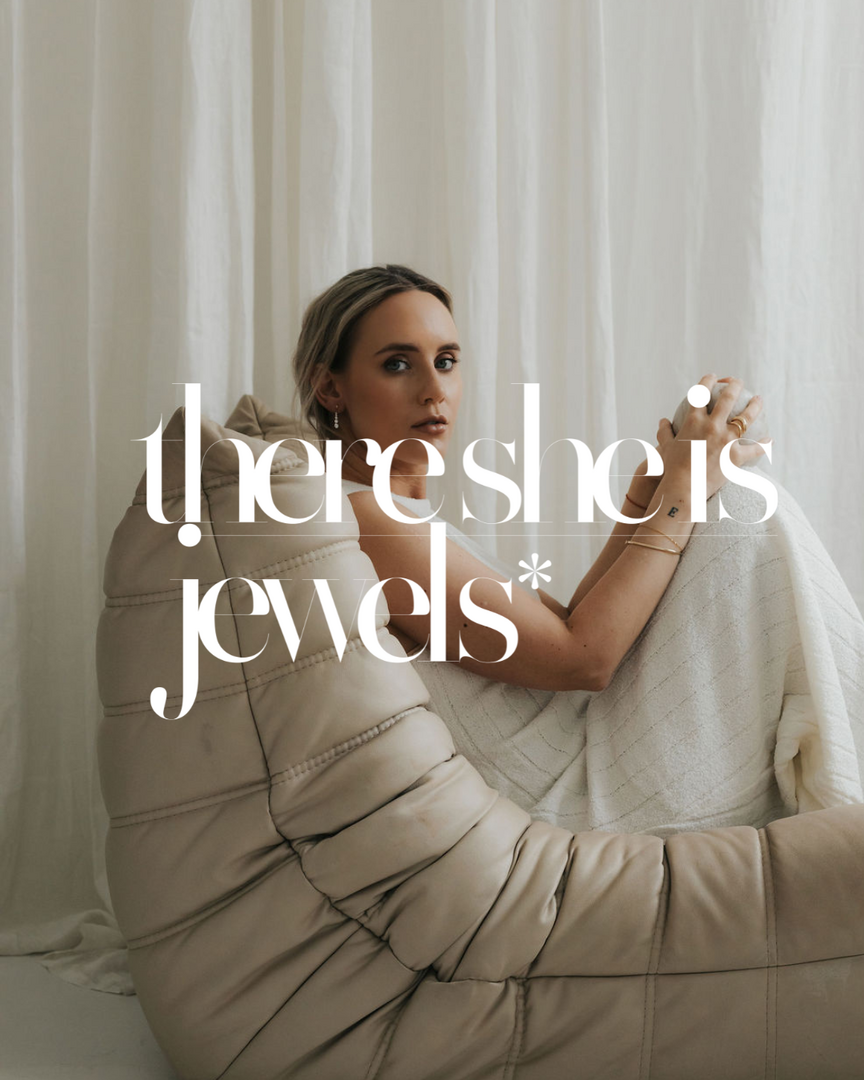 Lady looking to camera sitting on chair with shop name there she is jewellery written on top.
