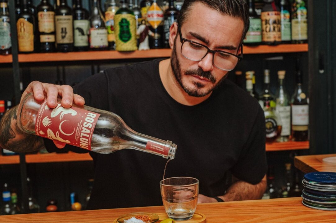 A man standing behind a bar, pouring a drink into a glass.