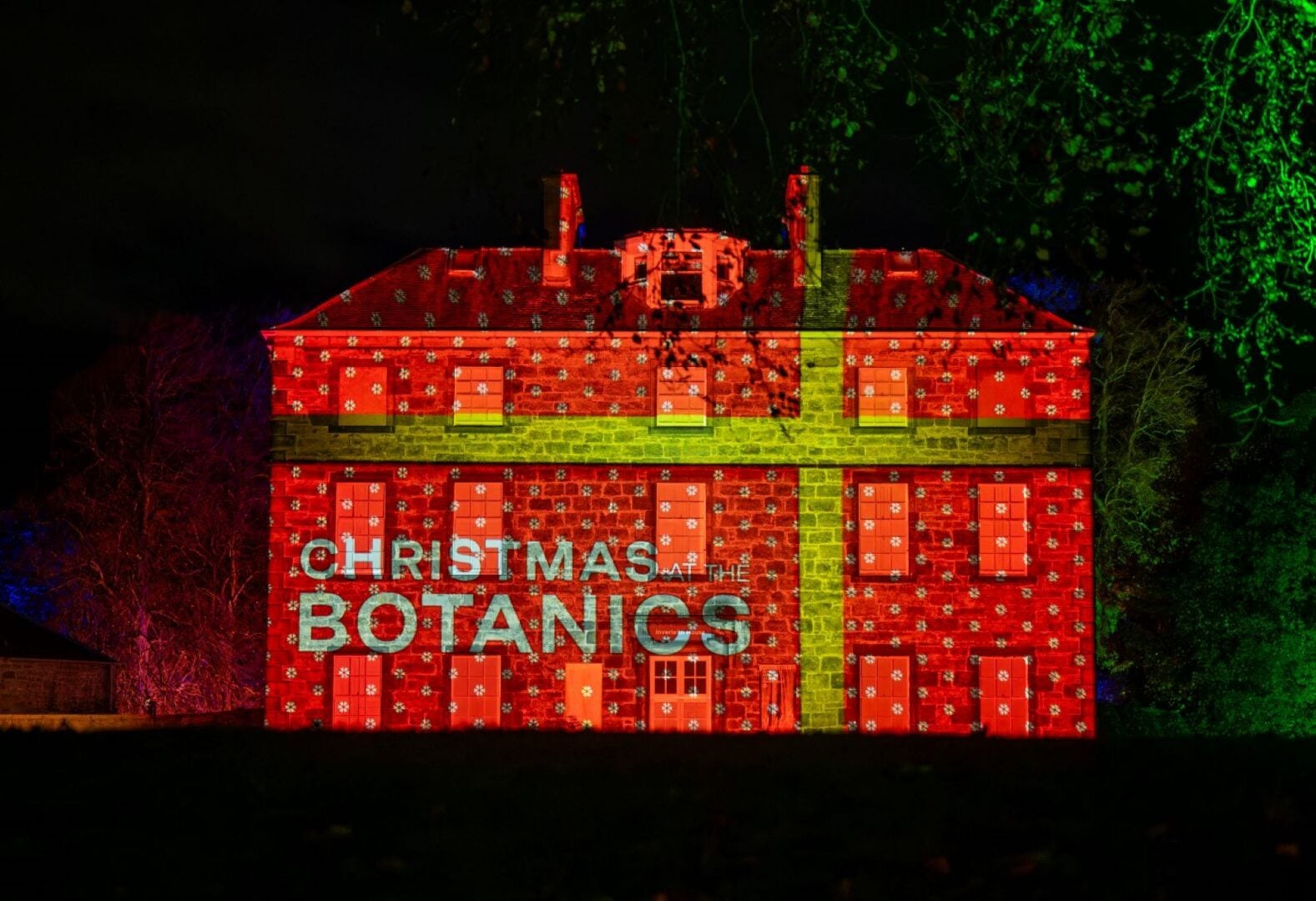 A large stone building, illuminated with red and yellow lights.