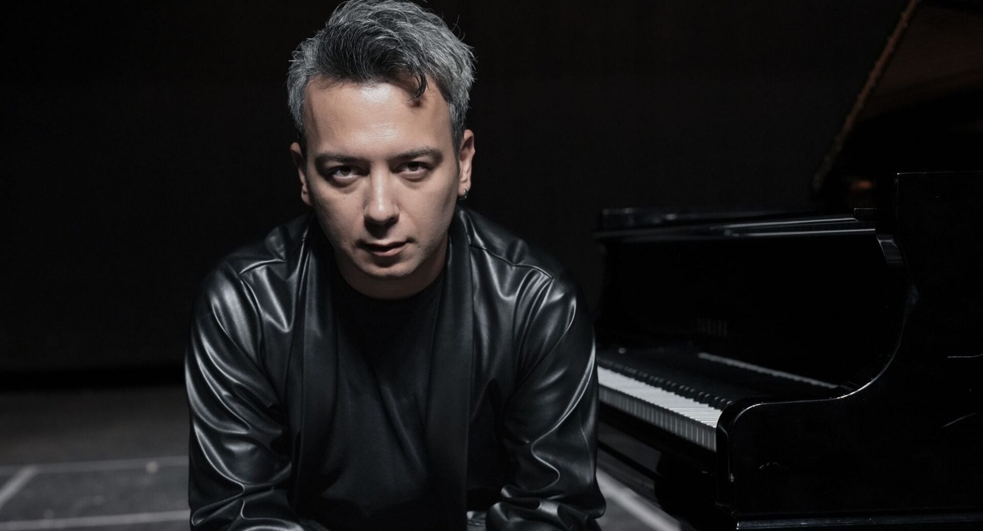 A man sitting in to the side of a piano.