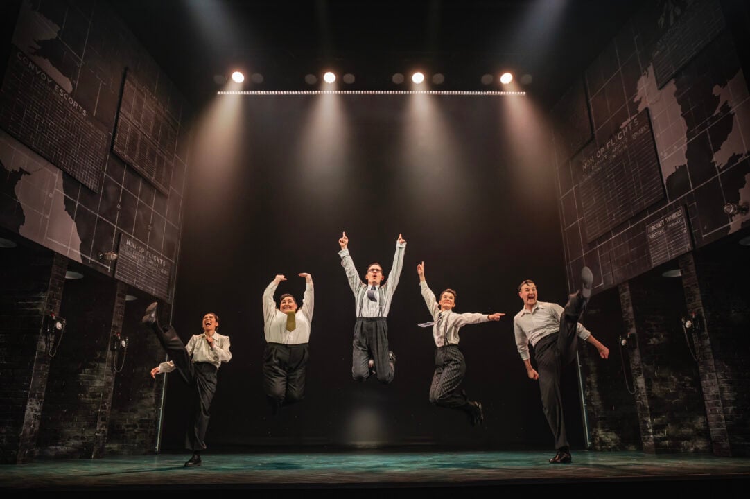 Five men and women jumping on stage