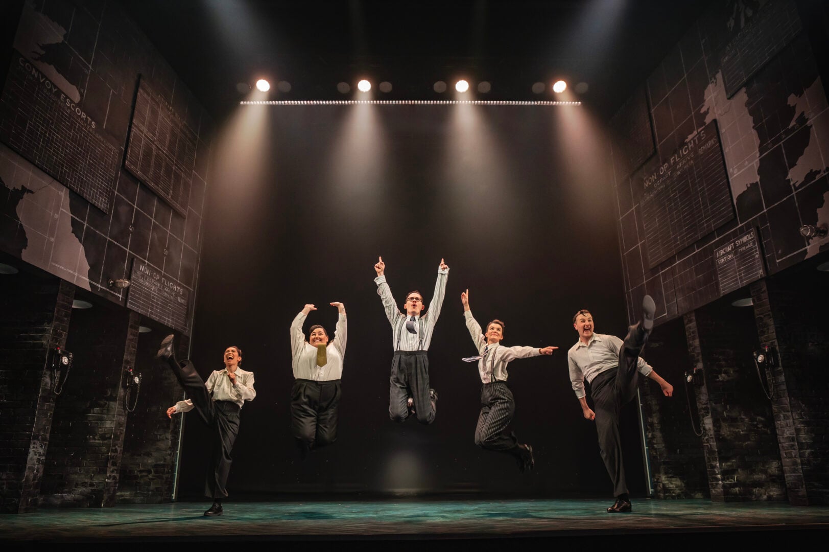 Five men and women jumping on stage