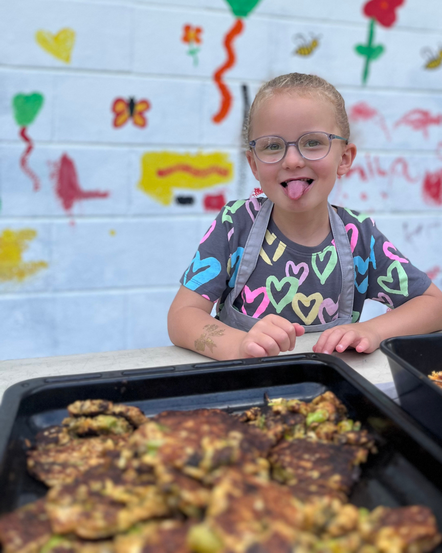 Youngster sticking out tongue at Edinburgh Food Social with plate of baked food