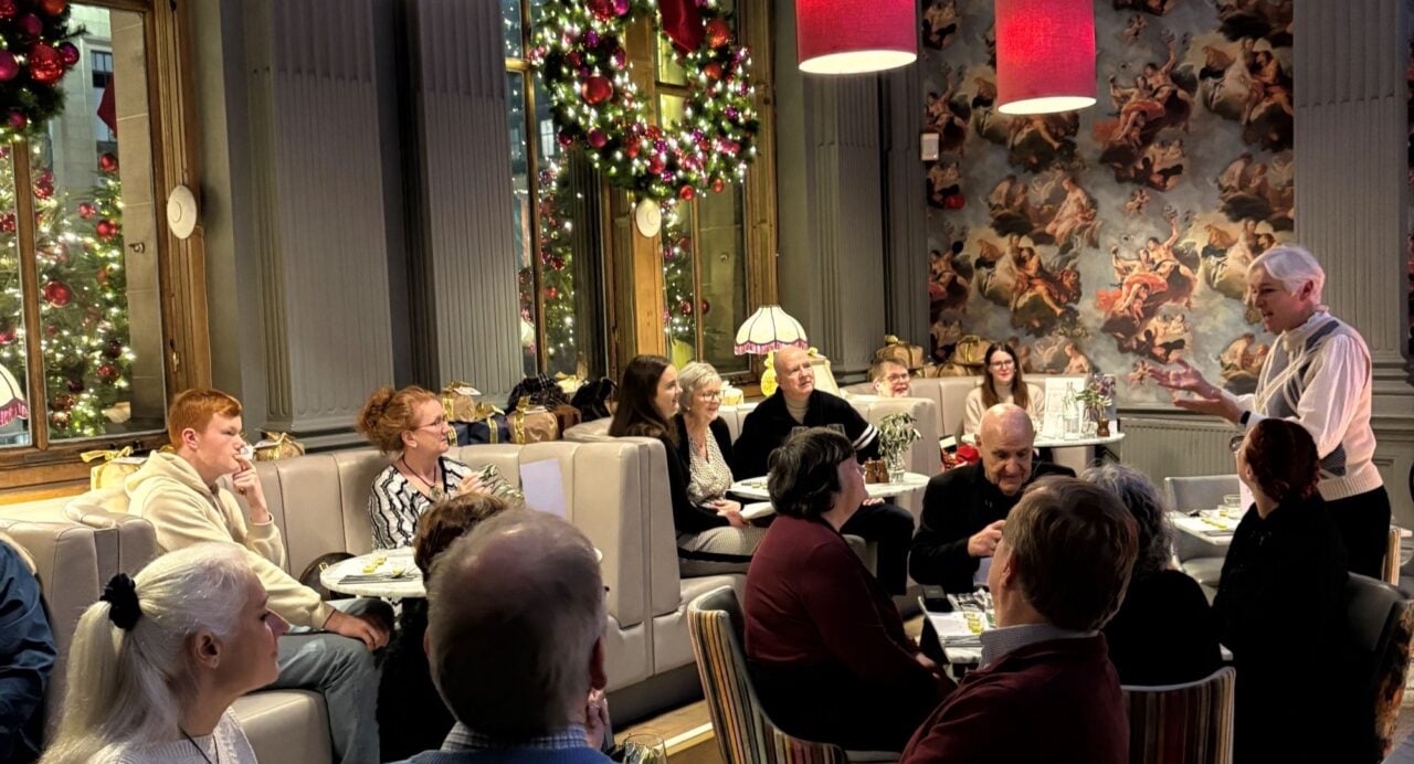 A room full of people, with a woman standing at the front talking.