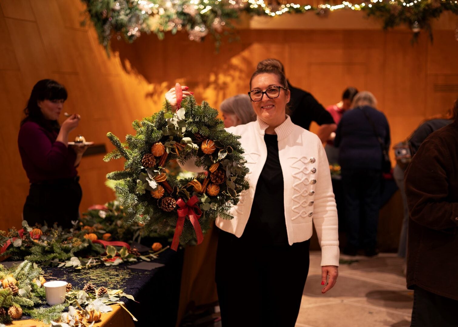 A woman holding up a Christmas wreath.