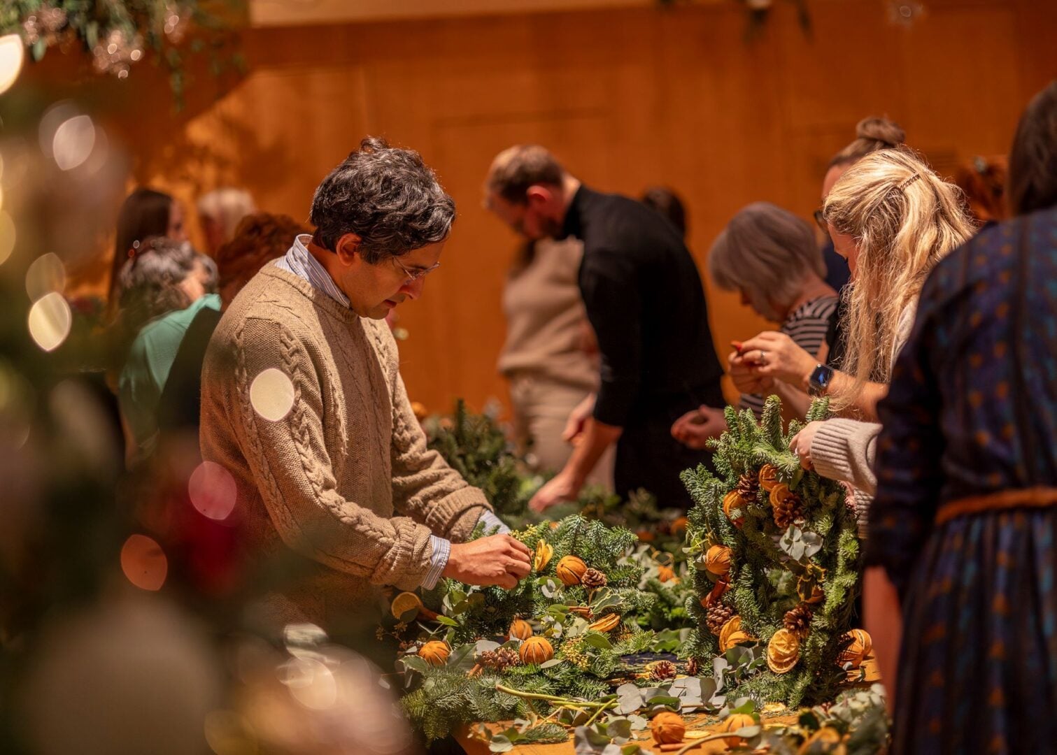 A room full of people making Christmas wreaths.